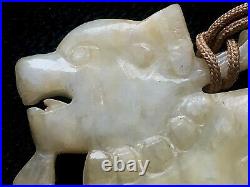 A Chinese celadon and russet jade pendant, 19th/20th century hand carved Foo Dog